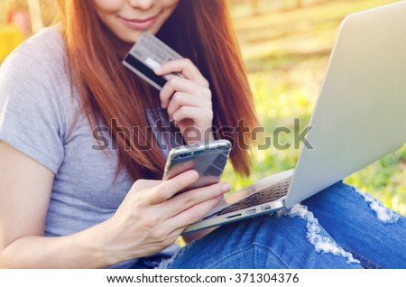 Mobile payments. Female (Focused) hands using smartphone and (Blurred) credit card with laptop for online shopping, m-banking.