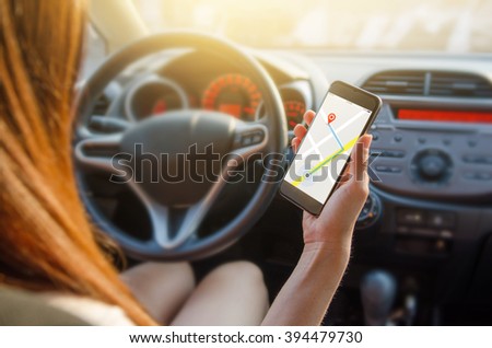 Close up hand woman using navigation or gps on mobile smartphone. Blurred car interior background. Viewing location map in network via smartphone during road trip