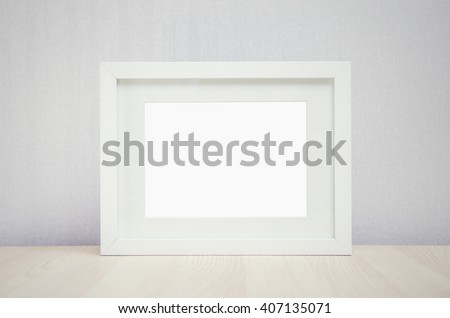 blank white picture frame on the wall and the table wood