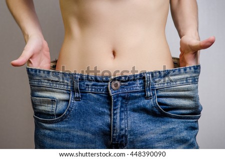 Slim Waist of Young Woman thin body with perfect, showing her jeans after successful diet or fitness, Weight loss and slimming concept.