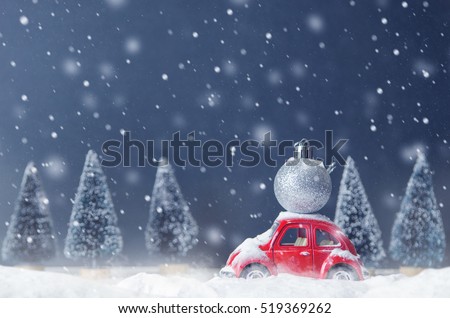 Silver ball christmas on red car toy with blurred tree background and snow. Christmas holiday celebration and new year 2017 background concept, copy space, filter effect.