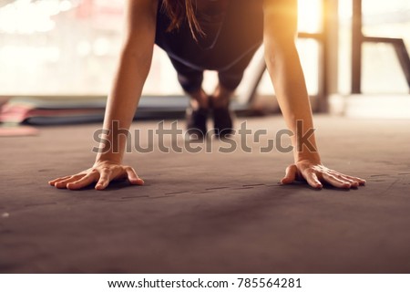 Close up woman hand doing push ups exercise in a gym in morning, sunlight effect.