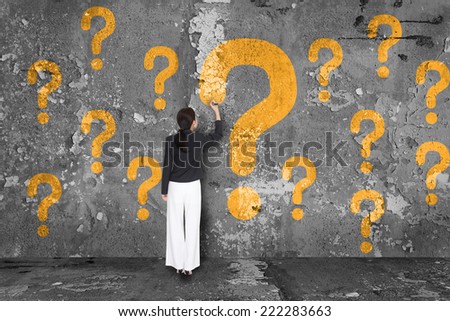 Businesswoman drawing question mark on wall