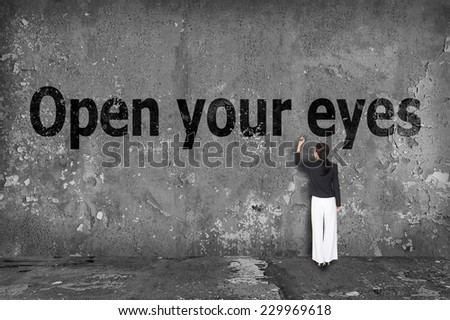 businesswoman drawing open your eyes on the wall