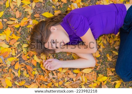 young woman in violet shirt on autumn leaves