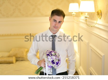 Handsome young man in a suit posing with a bright bouquet