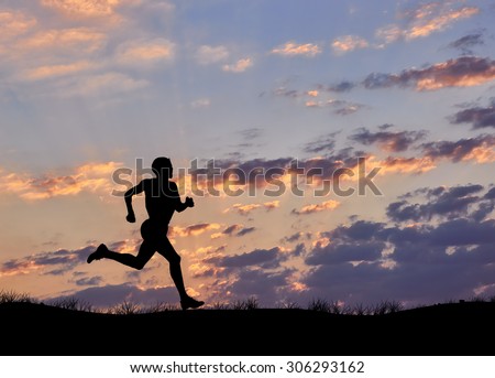 Silhouette of man runner against the evening cloudy sky