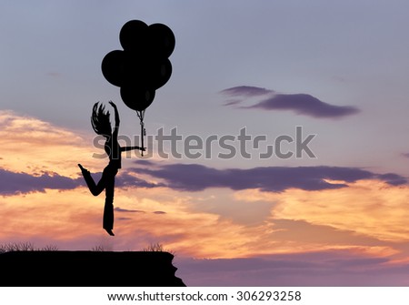 Silhouette of a girl jumping with balloons in the sky against the evening cloudy sky with sun rays with a purple tinge