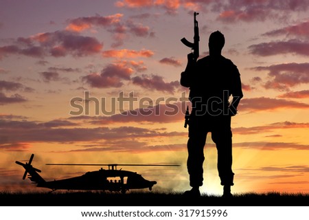 Silhouette of a soldier and helicopter at sunset