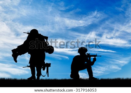 Concept of war. Silhouette of a soldier carries a wounded soldier on a background of sky