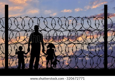 Concept of security. Silhouette of refugee men and metal fence with barbed wire on the background of night sky