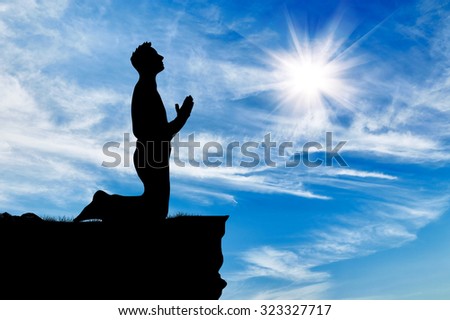 Silhouette of man praying at the top against the beautiful cloudy sky