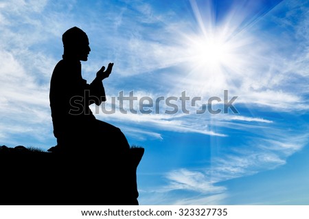 Islamic religion. Silhouette of man praying at the top on a background cloudy sky