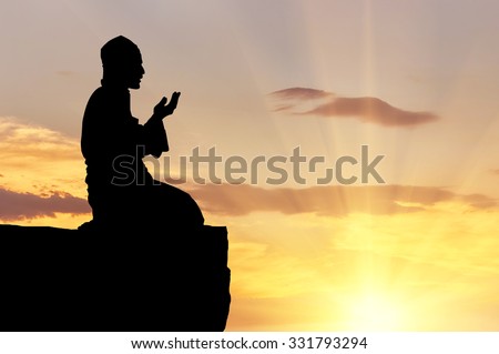 Concept of Islam is the religion. Silhouette of man praying on a hilltop at sunset
