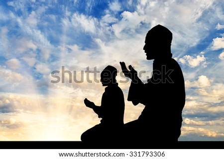 Concept of religion Islam. Silhouette of two men praying at sunset