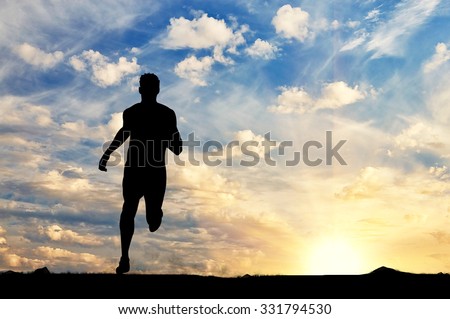 Concept of sport. Silhouette of runner against the evening sky