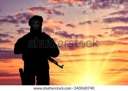 concept of terrorism. Silhouette of a terrorist with weapons and a skull face at sunset