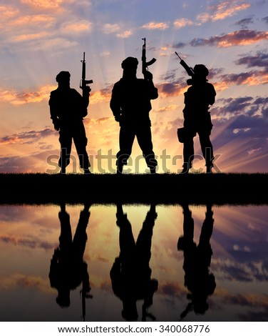 Concept of a terrorist. Silhouette of terrorists with a rifle and a reflection on the water at sunset