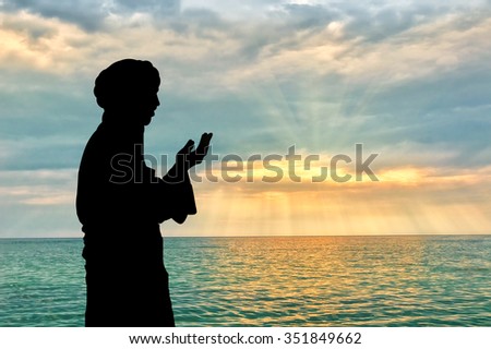 Concept of Islamic culture. Silhouette of man praying on the background of the sea and a beautiful sunset