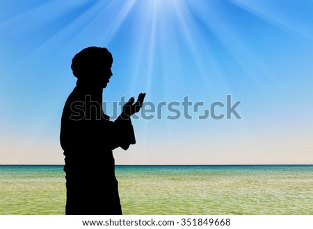 Concept of Islamic culture. Silhouette of man praying on the background of the sea in the rays
