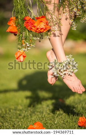 Beautiful female legs with flower dress on natural green background