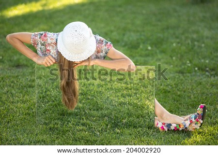 Sensual young woman in the green garden. Showing summer sign woman. Woman showing empty blank green grass sign board with copy space for text or design. soft daylight