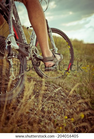 Low angle view of cyclist riding mountain bike on rocky trail at sunset