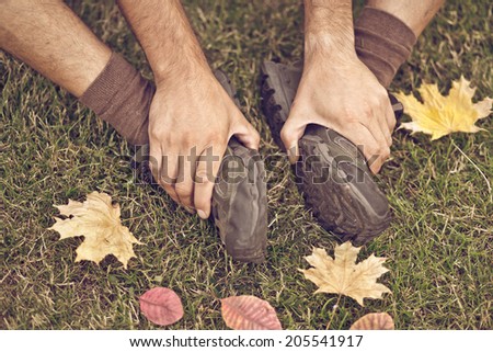 Close up of feet of a runner relaxing after running in autumn leaves and and grass. toned old image. focus on shoes