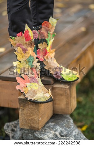 Closeup autumn woman legs with creative autumn boots. Autumn concept