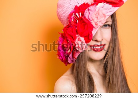 Fashion woman in hat over orange background, focus on face