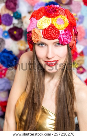 Fashion woman wearing funny summer hat over flowers background. Summer beauty woman concept