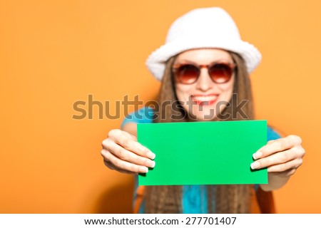Happy hipster traveler woman with boarding card over vibrant background, focus on green card