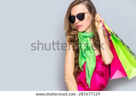 Shopping woman holding shopping bags looking to the side on grey background wearing bright clothing