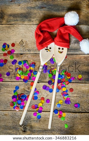 Funny wooden christmas background for a menu card with wooden spoons wearing funny christmas hats. creative idea