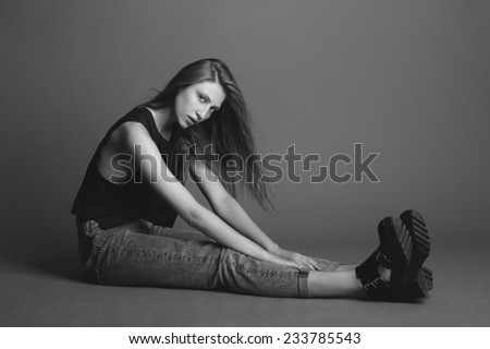 Young beauty blond woman seating in yoga pose, black and white, grey background.