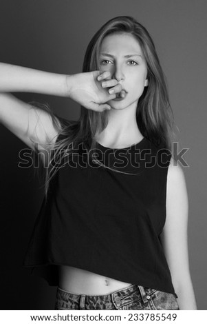 Young beauty blond woman standing with the hand on her face, black and white, grey background.