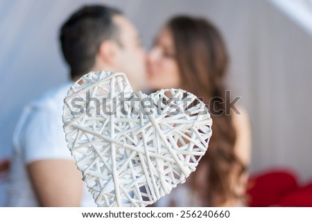 Wickerwork white heart. In the background are kissing man and woman. Spring, love and romantic relationship