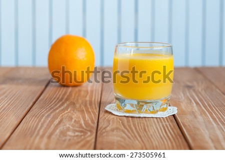 Glass of freshly pressed orange juice with whole fruit on wooden table. healthy food, diet and detoxification
