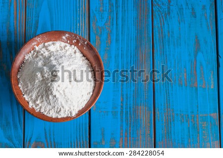 Bowl of wheat flour on vintage wood table from above. Rustic background with free text space