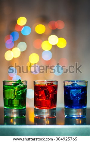 Three shot glasses with cocktail or liquor. Happy party background.
