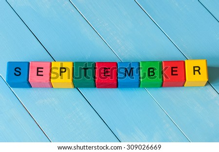 September sign on color wooden cubes with light blue wood background. Back to school time.