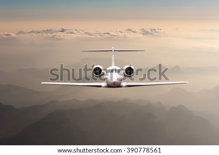 Airplane fly over clouds and Alps mountain on sunset. Front view of a big passenger or cargo aircraft, business jet, airline. Transportation, travel concept
