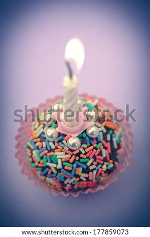 Lit birthday candle on colorful background