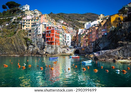 Riomaggiore, Liguria, Italy. The beautyful village of Riomaggiore as you can see it from the see, vith colorful houses reflecting themselves in the water. Blue sky.