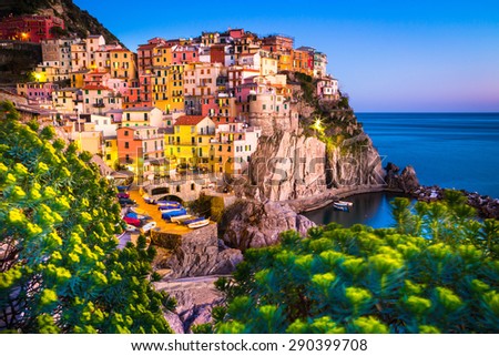 Manarola, Liguria, Italy. The wonderful Manarola village as you can see it from the mountain above. Quiet sky and peaceful sea, flowers on the foreground.