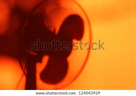 Electric fan shadow among orange wall. Heat and coolness concept. Cool theme background for summer advertising