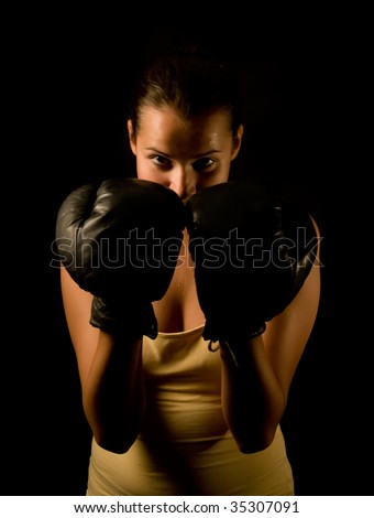 Girl in black boxing gloves on black background