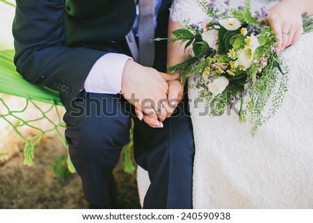 Bride and groom holding hands. Wedding bouquet in bride's hand.