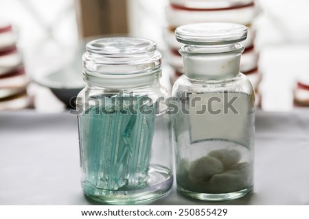 Bottles with glass pieces and swabs in a lab; Petri dishes stacked on the background
