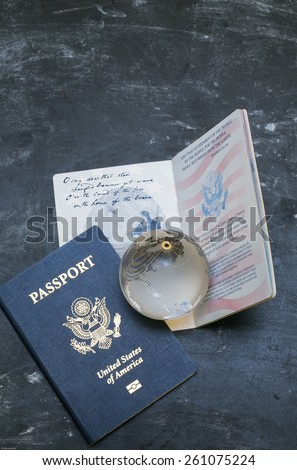 Two US passports on black background. American citizenship. Traveling around the world. Small glass globe on open document.